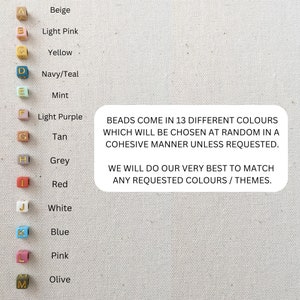 May include: A chart showing 13 different colors of beads with letters A through M next to each color. The colors are beige, light pink, yellow, navy/teal, mint, light purple, tan, grey, red, white, blue, pink, and olive. The text below the chart reads: "BEADS COME IN 13 DIFFERENT COLOURS WHICH WILL BE CHOSEN AT RANDOM IN A COHESIVE MANNER UNLESS REQUESTED. WE WILL DO OUR VERY BEST TO MATCH ANY REQUESTED COLOURS / THEMES."