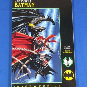 May include: Comic book cover featuring Spawn and Batman. The cover has a black background with lightning bolts and the title "Spawn Batman" in yellow. The artwork depicts the characters in action poses.