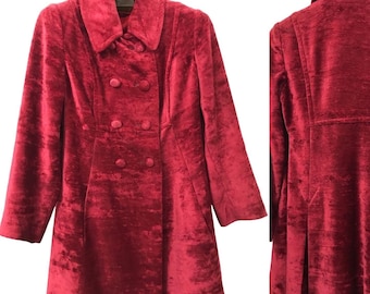 May include: A red velvet coat with a double breasted closure and a collar. The coat has a fitted waist and a flared skirt.