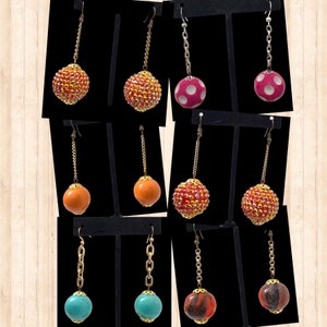 May include: Assortment of dangle earrings with various colored beads. The beads are round and feature different patterns, including polka dots, stripes, and solid colors. The earrings are displayed on a black background.