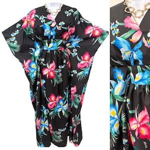 May include: A black floor-length kaftan dress featuring a vibrant floral print with bright pink and blue orchids, green palm leaves, and the word Aloha printed in white. The garment has a V-neckline, wide kimono-style sleeves, and a fitted waist.