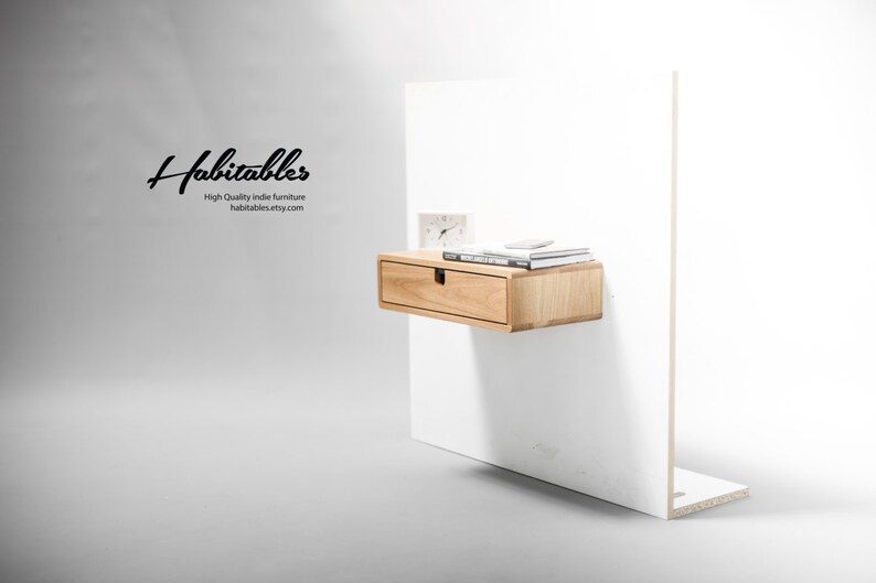 May include: A light wood floating shelf with a single drawer and a small clock and books on top. The shelf is mounted on a white wall. The text "Habitables High Quality indie furniture habitables.etsy.com" is visible in the image.
