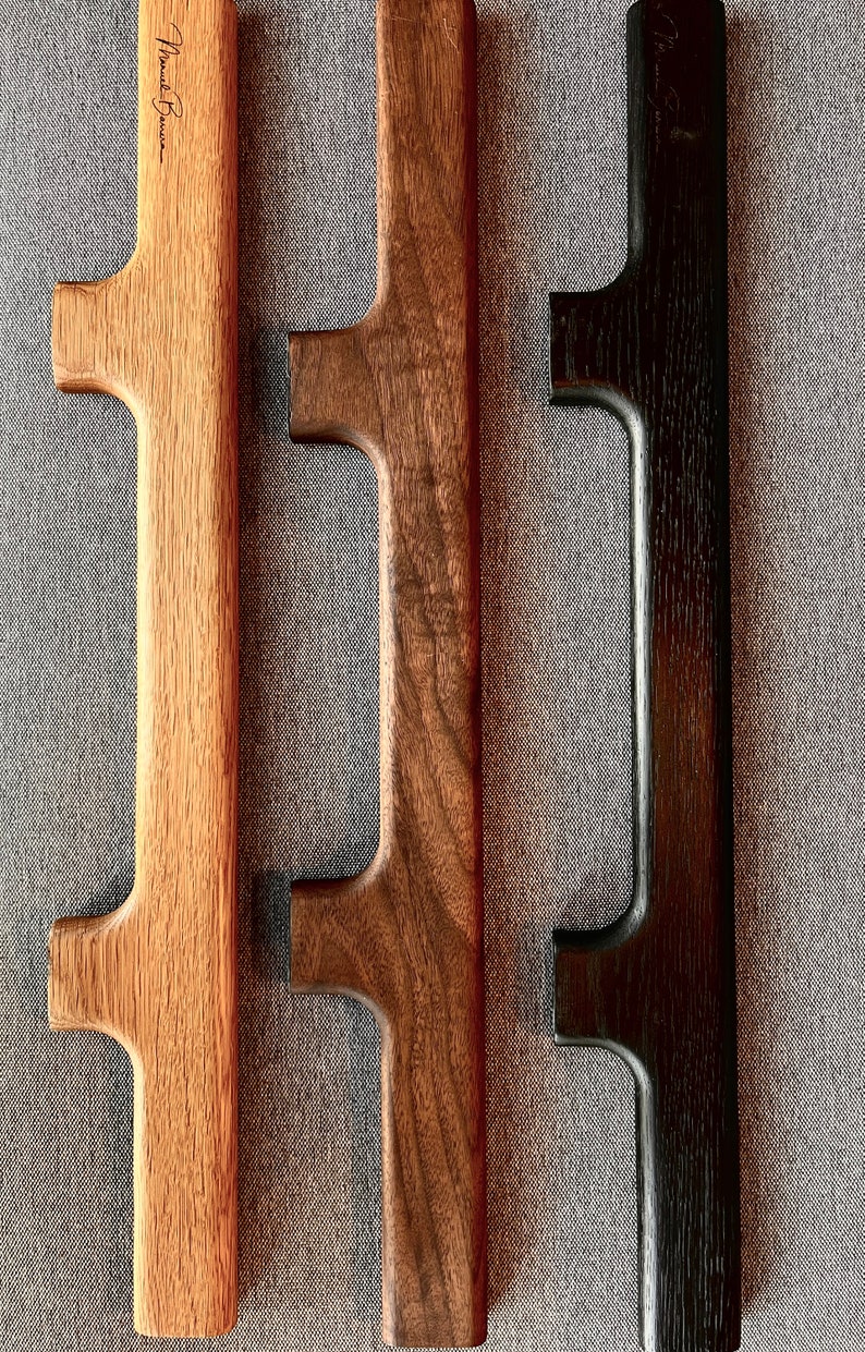 May include: Three wooden handles with different finishes: light wood, dark wood, and black. The handles have a simple, rectangular design with a cutout in the center.