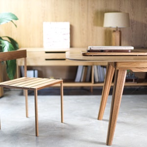 May include: A wooden table with a light wood finish and a single chair. The table has a rounded edge and four legs. The chair has a slatted seat and back.