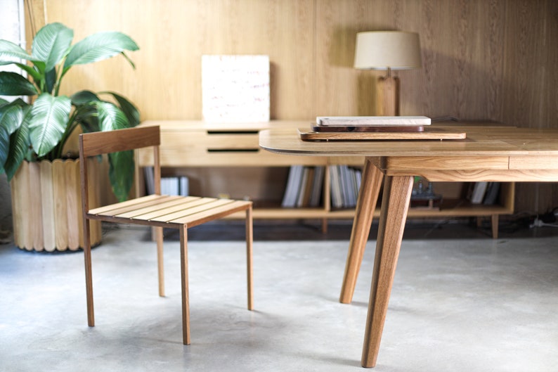 May include: A wooden table with a light wood finish and a single chair. The table has a rounded edge and four legs. The chair has a slatted seat and back.