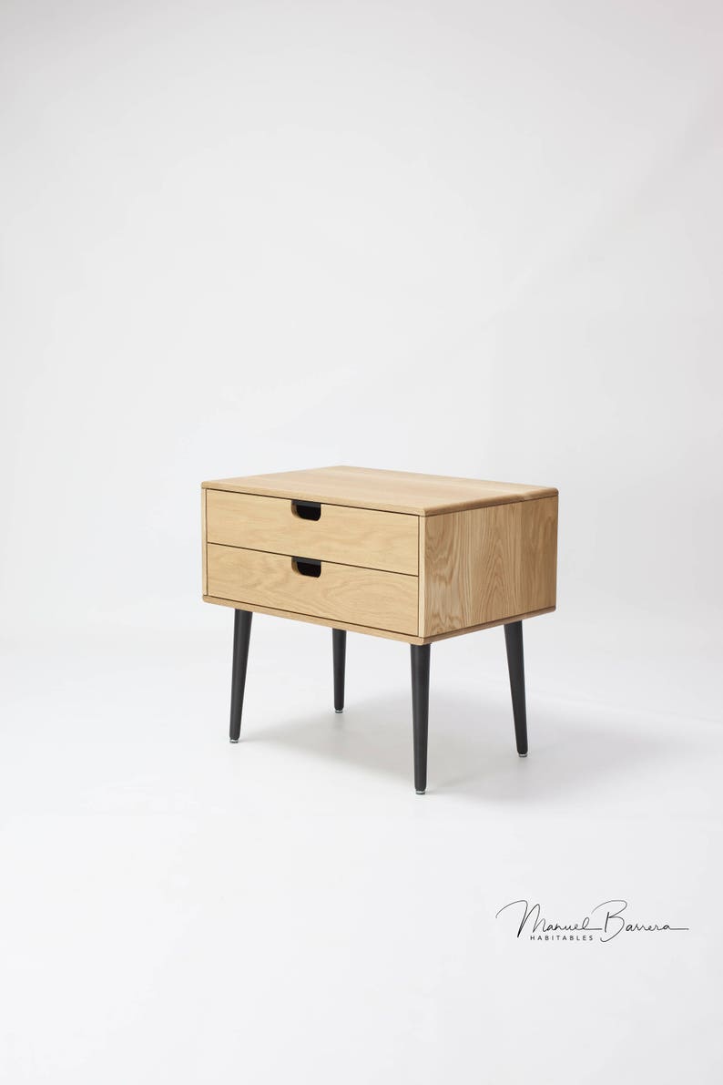 May include: A wooden nightstand with two drawers and black legs. The nightstand is made of light wood and has a simple, modern design.