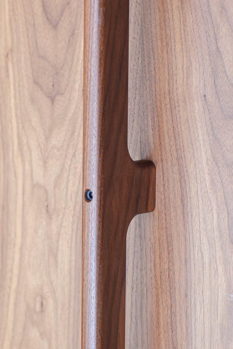 May include: A close-up of a wooden door handle with a dark brown finish. The handle is made of solid wood and has a simple, elegant design.