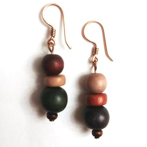 May include: A pair of earrings with three wooden beads each. The beads are brown, beige, green, and dark brown.