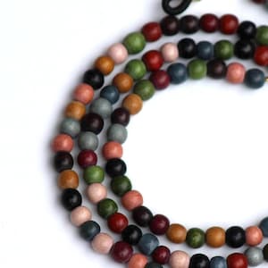 May include: A multi-strand eyeglass chain with colorful wooden beads. The beads are in various colors, including pink, green, blue, and brown. The chain has gold-colored metal accents and black rubber loops for attaching to glasses.