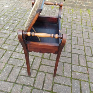 May include: A dark brown wooden sewing table with a hinged lid and a storage compartment. The table has curved legs and a handle on each side. The lid is partially open, revealing the interior. The table is approximately 61 cm tall.