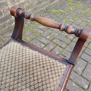 May include: A vintage wooden chair with a woven seat and a curved backrest. The chair has a dark brown finish and a decorative handle. The seat is a light tan colour with a repeating pattern. The chair is an antique piece.