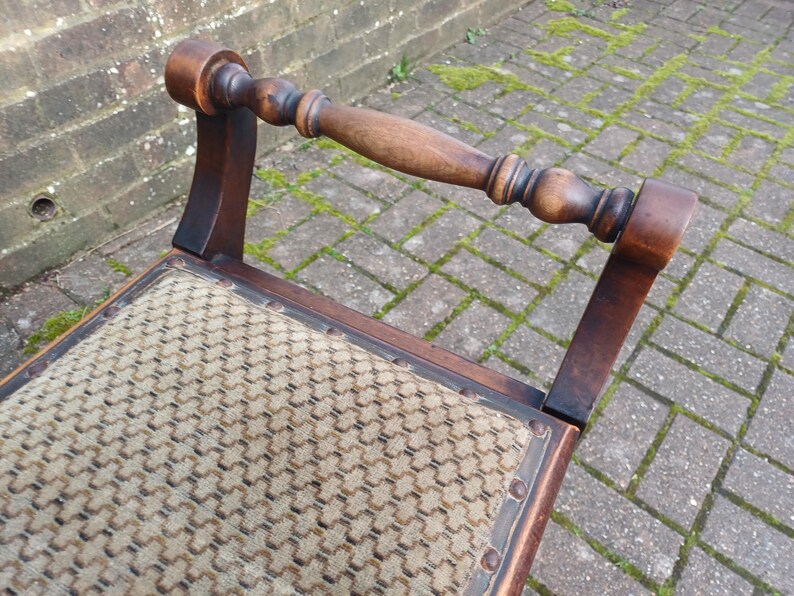 May include: A vintage wooden chair with a woven seat and a curved backrest. The chair has a dark brown finish and a decorative handle. The seat is a light tan colour with a repeating pattern. The chair is an antique piece.