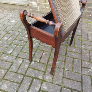 May include: A dark brown wooden side table with a storage compartment and patterned fabric seat. The table has curved legs and scrolled armrests. The design is reminiscent of antique furniture, with a classic, elegant aesthetic.