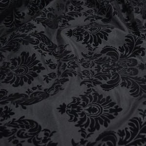 May include: Black damask fabric with a raised pattern. The fabric has a soft, luxurious feel and is perfect for upholstery, curtains, or other home decor projects.