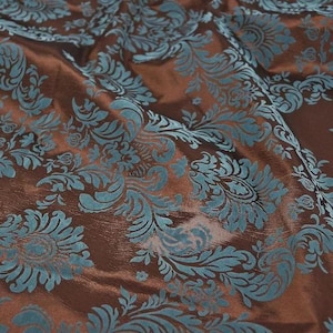 May include: Brown fabric with a teal blue damask pattern.