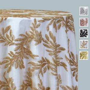 May include: A white tablecloth with a gold leaf design. The gold leaves are embroidered across the fabric. The tablecloth is round and has a satin finish. Additional color options are shown in the corner.