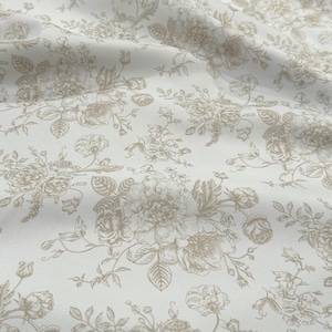 May include: A white fabric featuring a repeating floral pattern in a light beige or tan color. The design consists of detailed line-drawn roses, buds, and leafy stems scattered across the surface, creating a soft, monochromatic botanical print.