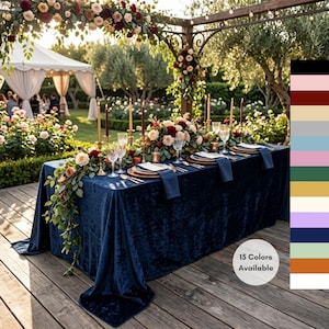 May include: A deep navy blue velvet tablecloth draped over a long rectangular table set for a formal event. The table features floral centerpieces, gold candlesticks, glassware, and napkins. A color palette chart on the right displays 15 colors available.