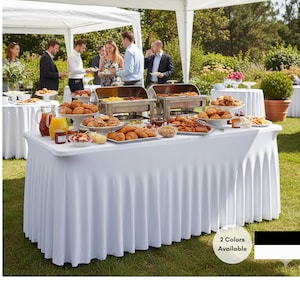 May include: A white buffet table with a pleated skirt, laden with food and drinks, set up outdoors under a white tent. Guests are visible in the background. The image includes the text "2 Colors Available".