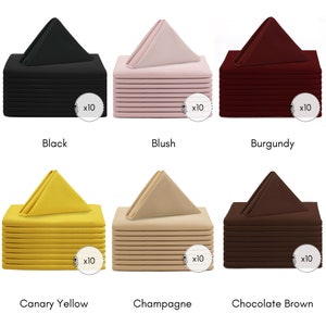 May include: Set of 10 dinner napkins in six colours: black, blush, burgundy, canary yellow, champagne, and chocolate brown. Each napkin is folded into a triangle shape and stacked in a pile.