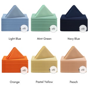 May include: Set of 10 napkins in six colours: light blue, mint green, navy blue, orange, pastel yellow, and peach. Each napkin is folded into a triangle shape and stacked on top of each other.