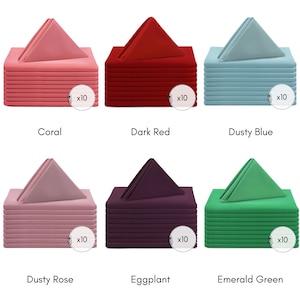 May include: Set of 10 dinner napkins in six different colours: coral, dark red, dusty blue, dusty rose, eggplant, and emerald green. Each napkin is folded into a triangular shape and stacked on top of each other.