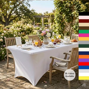 May include: A white fitted tablecloth covers a rectangular table set for an outdoor meal. The table is surrounded by wooden chairs and set with plates, glasses, and a floral centerpiece. The image includes the text "19+ Colors Available."