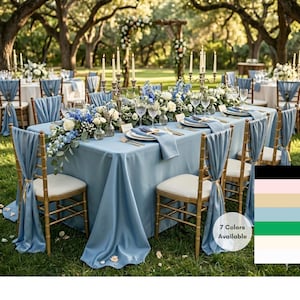 May include: A beautifully set outdoor wedding reception table with a light blue tablecloth, matching chair sashes, and gold chairs. The table is decorated with white and blue floral arrangements, candles, and place settings. The image shows a selection of 7 colors available.