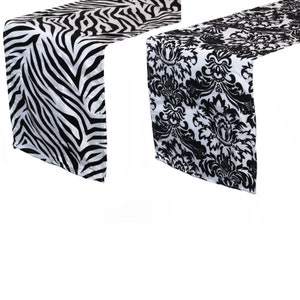 May include: Two table runners, one with a black and white zebra print and the other with a black and white damask pattern.