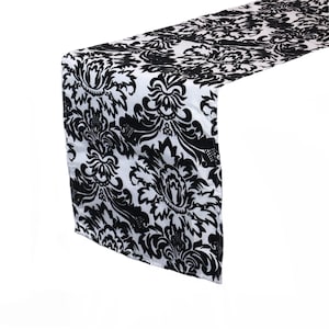 May include: Black and white damask table runner with a floral pattern.