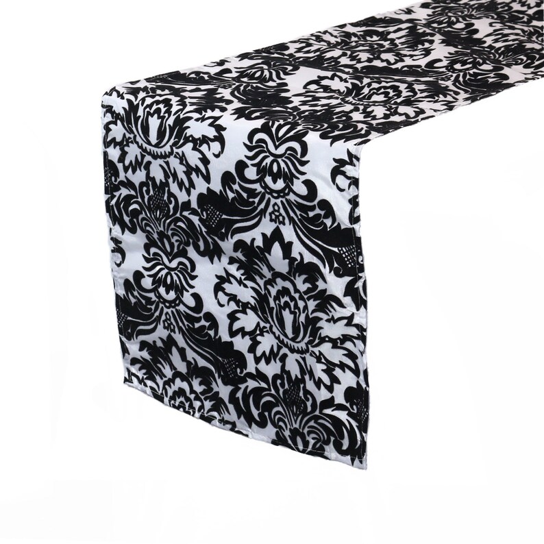 May include: Black and white damask table runner with a floral pattern.