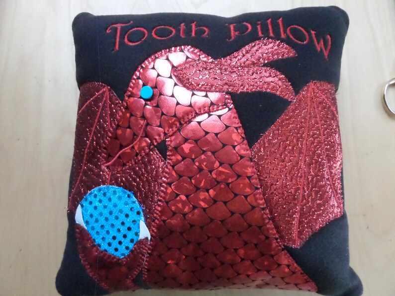 Fierce dragon is holding a jewel where a lost tooth can be put to await the tooth fairy. image 1