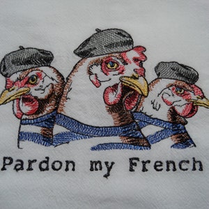 May include: Three embroidered chickens wearing blue and white striped berets and scarves with the text "Pardon my French" below them.