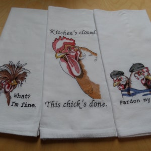 May include: Three white kitchen towels with embroidered chickens and humorous sayings. The first towel features a chicken with a mohawk and the text "What? I'm fine." The second towel features a rooster with the text "Kitchen's closed. This chick's done." The third towel features three chickens wearing berets and the text "Pardon my French."