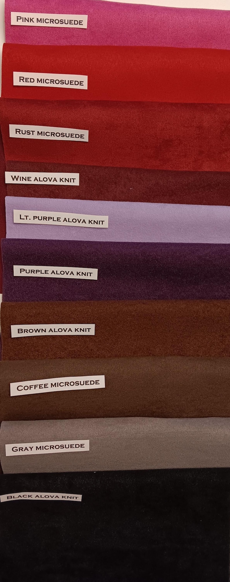 Pu&ograve; includere: Primo piano di dieci campioni di tessuto in diversi colori e trame. I campioni sono etichettati con i loro nomi e tipi, tra cui "Microsuede rosa", "Microsuede rosso", "Microsuede ruggine", "Maglia Alova vino", "Maglia Alova viola chiaro", "Maglia Alova viola", "Maglia Alova marrone", "Microsuede caff&egrave;", "Microsuede grigio", e "Maglia Alova nero".