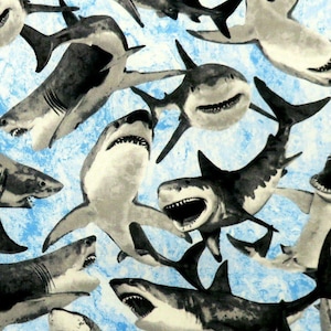 May include: A repeating pattern of sharks in shades of gray and black against a light blue background. The sharks are depicted in various poses, some with open mouths, showcasing their teeth. The design has a slightly textured appearance.