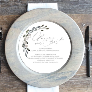 May include: A white card with a floral design and the text "Olivia and Grant" at the top. The card also includes a message of thanks to family and friends for their support.