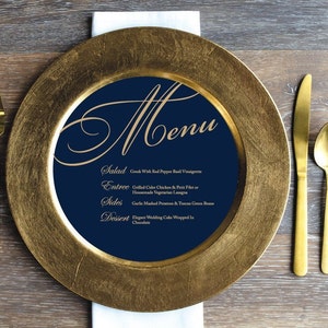 May include: A gold charger plate with a navy blue center featuring a gold menu with the words "Menu", "Salad", "Entree", "Sides", and "Dessert" with corresponding food items listed below each.