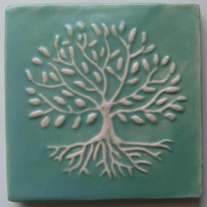 May include: A ceramic tile with a white tree of life design on a teal blue background.