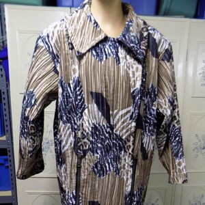 May include: A brown and white patterned jacket with a black zipper detail. The jacket has a collar and long sleeves.