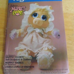 May include: A vintage Vogue Patterns craft pattern featuring a soft sculpture of Miss Piggy from Muppet Babies. The cover shows a doll in a pink dress and bonnet. The pattern number is 8967.