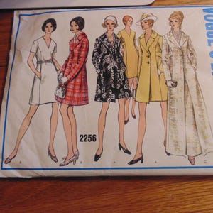 Könnte beinhalten: Ein Vintage-Schnittmuster von Vogue's Basic Design für ein Kleid und einen Mantel. Die Schnittmuster-Nummer lautet 2256. Das Schnittmuster zeigt fünf verschiedene Stile von Kleidern und Mänteln, darunter ein weißes Kleid, einen roten karierten Mantel, einen schwarz-weißen Blumenmantel, einen gelben Mantel und einen weißen Mantel.