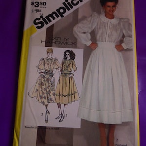 Può includere: Modello di cucito Simplicity numero 5360 per una blusa e una gonna. Il modello è per una blusa bianca con un colletto ad occhiello acquistato e una gonna bianca con un volant arricciato sul bordo. Il modello è di Cathy Hardwick.