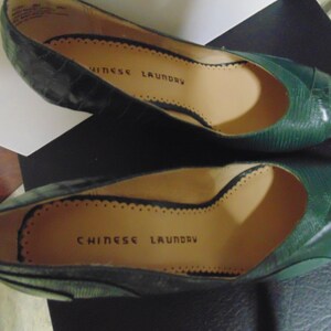 May include: A pair of green leather shoes with a pointed toe and a small heel. The shoes are labeled "Chinese Laundry" on the insole.