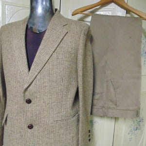 May include: A brown tweed blazer with two button closures and a matching pair of brown pants.