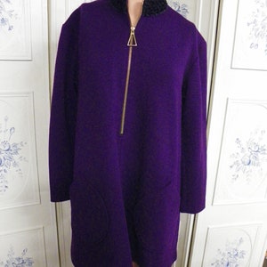 May include: A purple long-sleeved jacket with a gold zipper and black fur trim around the collar. The jacket has two large pockets on the front.