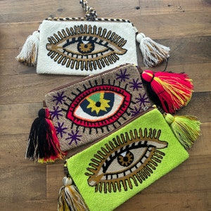 cartera wayuu con diseno de ojo turco y pom pompones