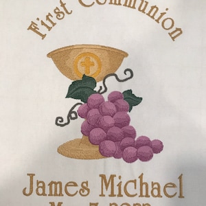 May include: Embroidered First Communion design on white fabric. Features a chalice with a cross, grapes, and the text "First Communion." Below, it reads "James Michael, May 7, 2022."