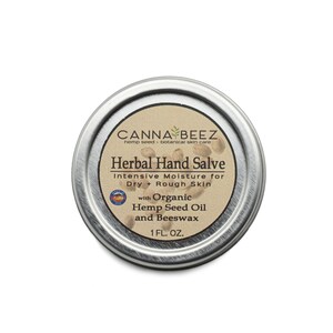 May include: A silver tin container with a label that reads "CANNA BEEZ hemp seed botanical skin care Herbal Hand Salve Intensive Moisture for Dry & Rough Skin with Organic Hemp Seed Oil and Beeswax 1 FL. OZ."