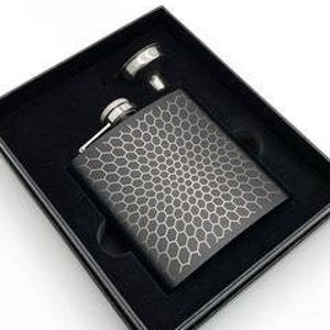 May include: A black flask with a geometric honeycomb pattern, presented in a black box. The flask includes a silver cap and is accompanied by a small silver funnel. The box is set against a white background.
